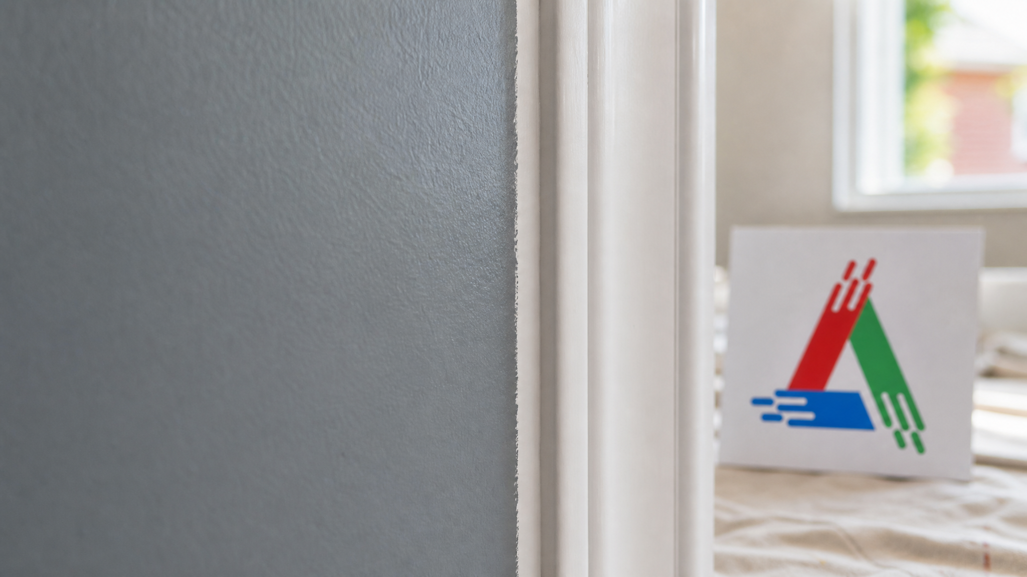 Close-up of a crisp cut-in line where a freshly painted wall meets white trim, showing smooth roller texture