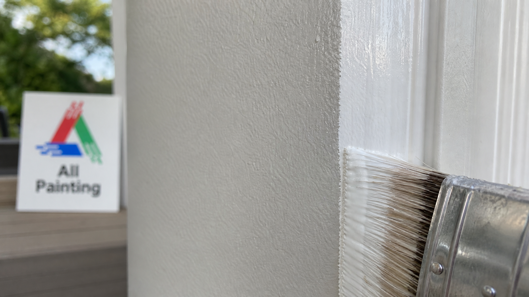 Close-up of a crisp painted cut-in line where a wall meets white trim, showing smooth roller texture in a Hamilton home