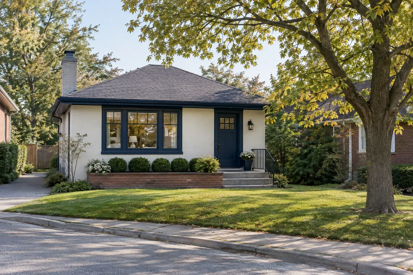 Postwar stucco bungalow freshly painted white with dark blue trim on a quiet street