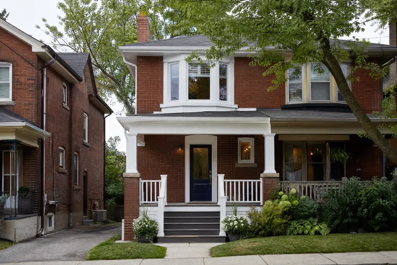After: the same house with crisp white trim and a navy front door