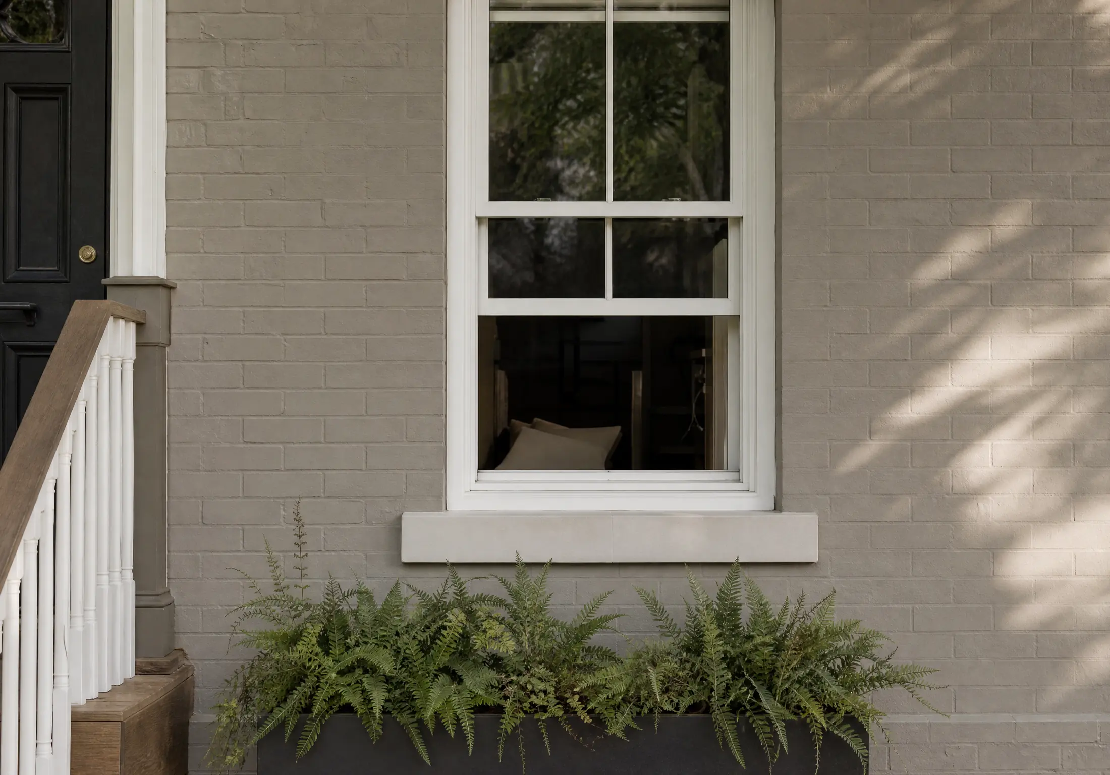 Close view of brick freshly painted soft greige with a white window frame