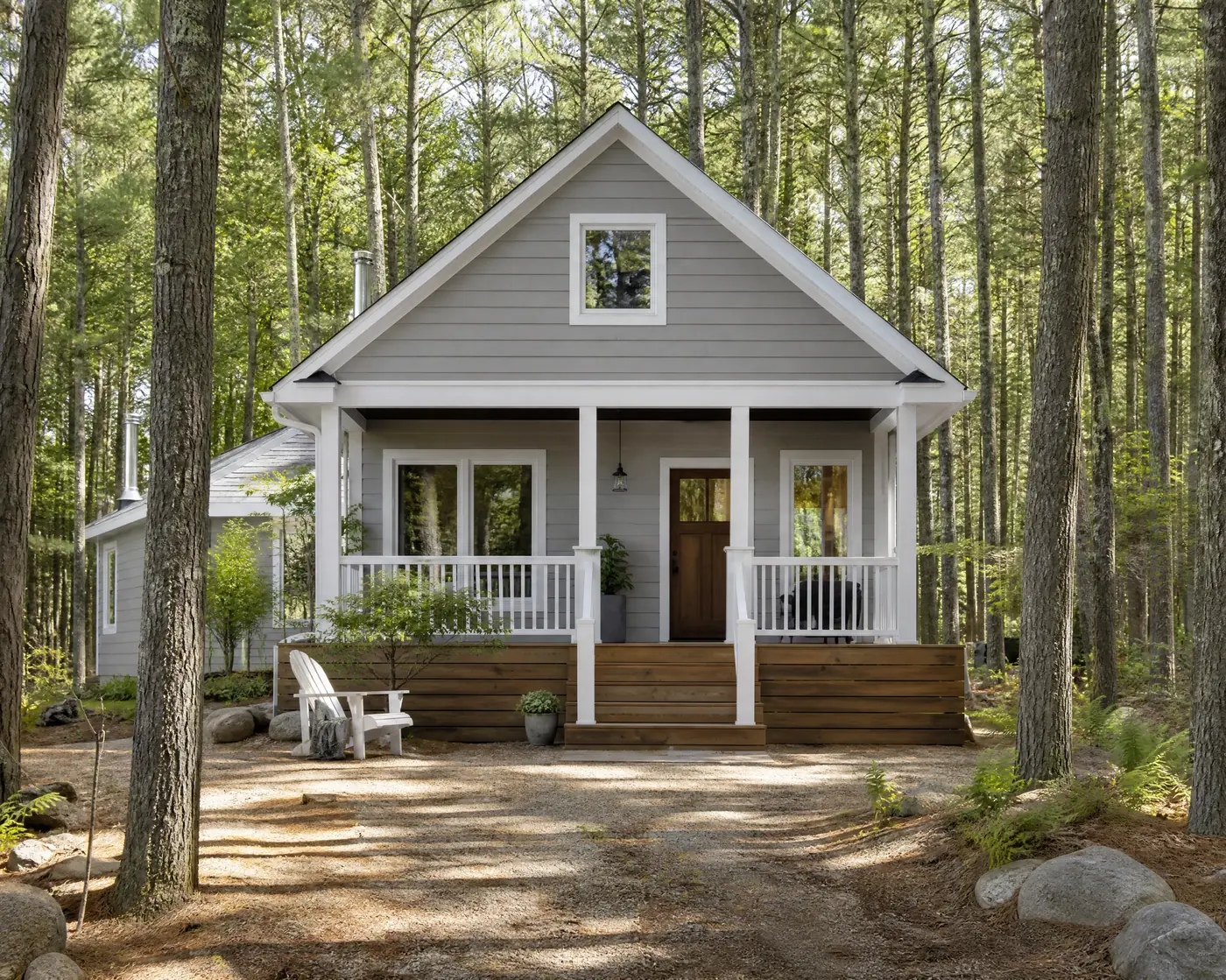 Wood-sided cottage freshly painted grey with white trim among pines