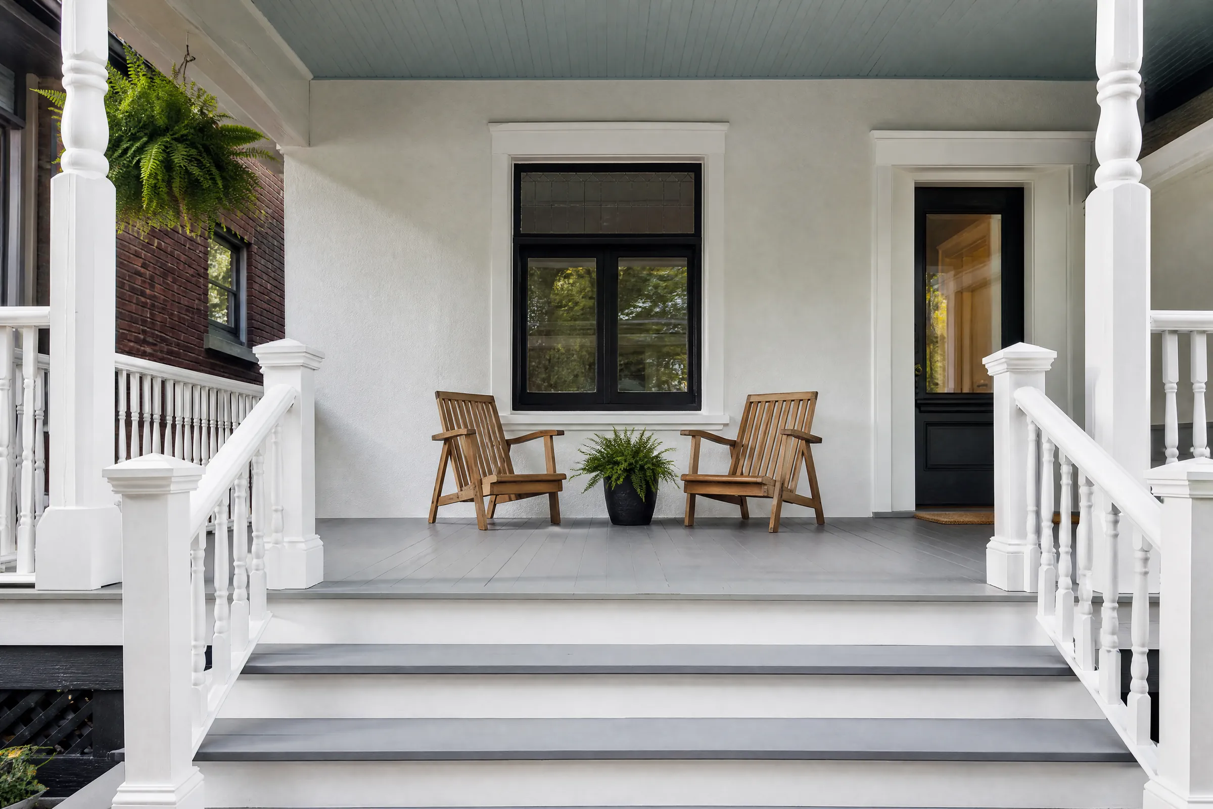 Wide front porch freshly painted with white posts and a slate-blue ceiling