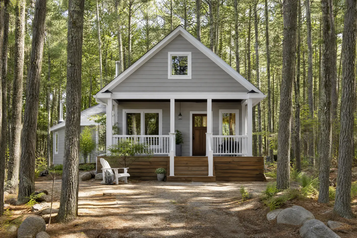 Wood-sided cottage freshly painted grey with white trim among pines