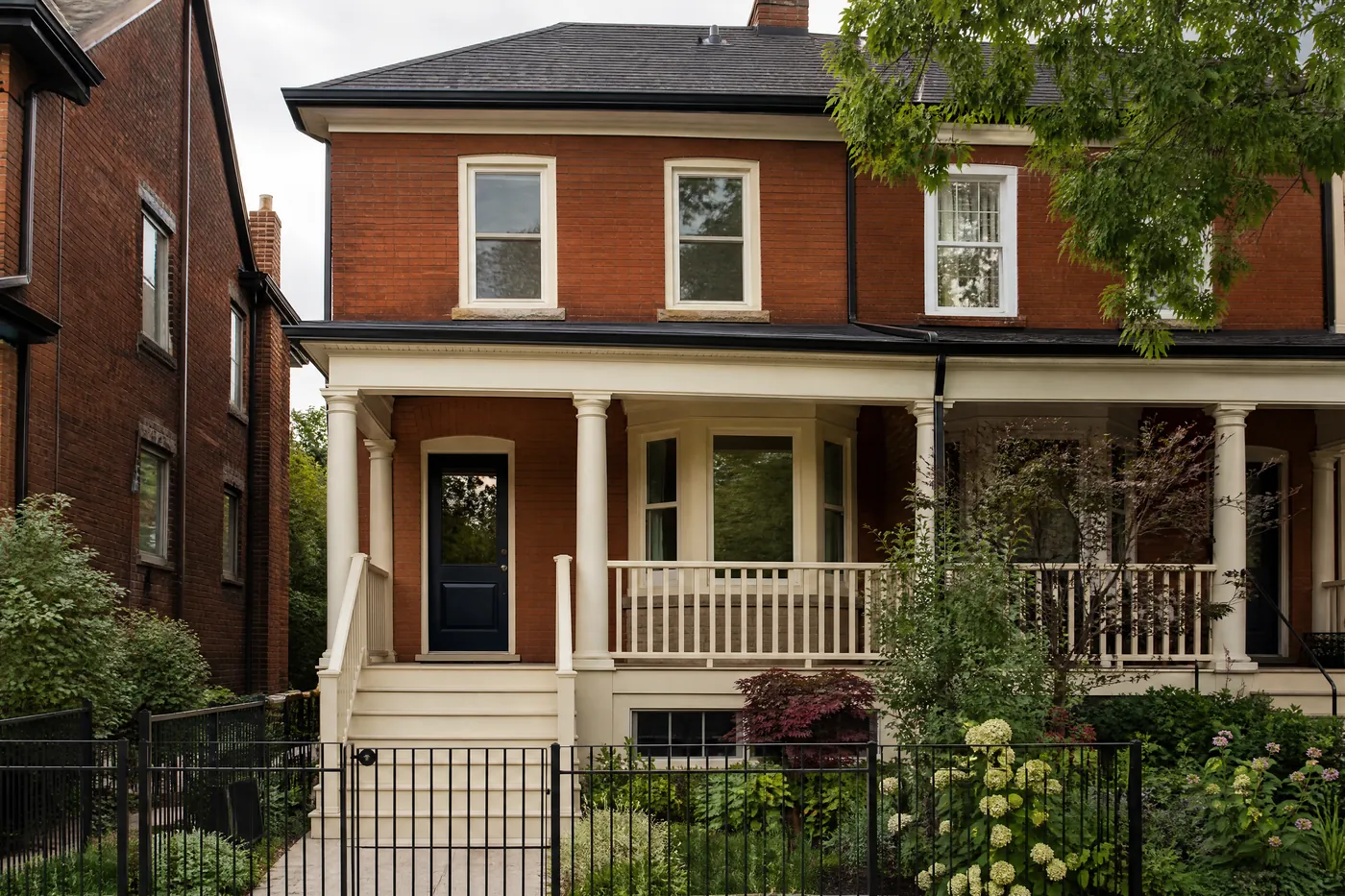 Red-brick semi with freshly painted cream window trim and a navy door