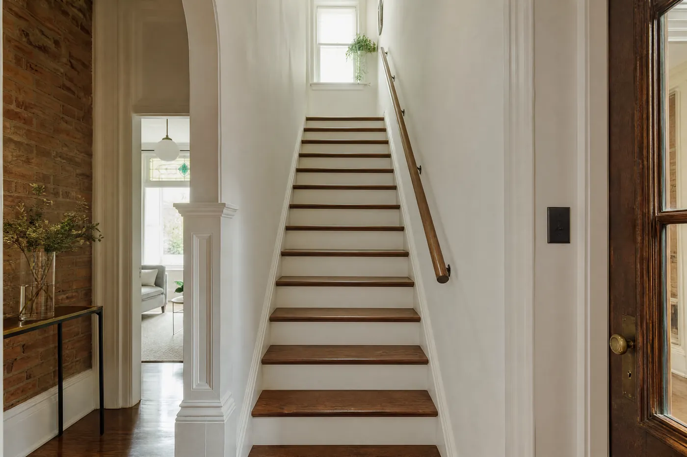 Closed staircase with freshly stained treads and a wall-mounted handrail